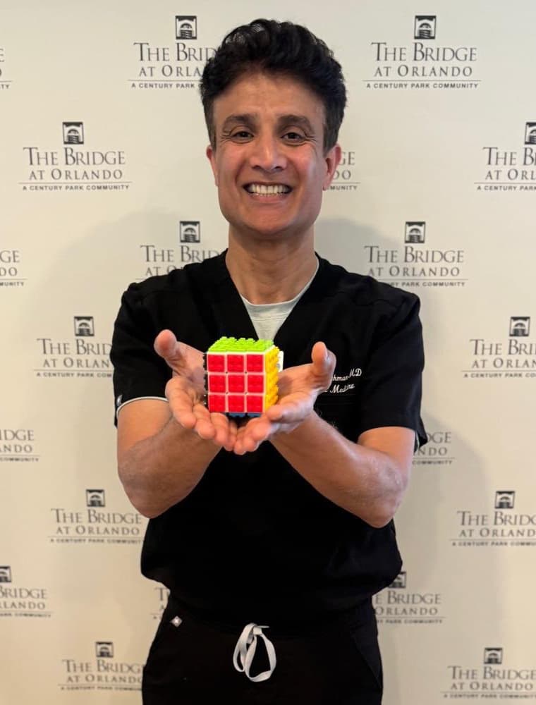 Dr. Arshad Rehman, smiling, holding Rehman’s Cube in both hands.